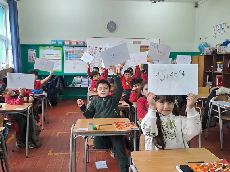Estudiantes de 3° básico muestran sus respuestas escritas en hojas